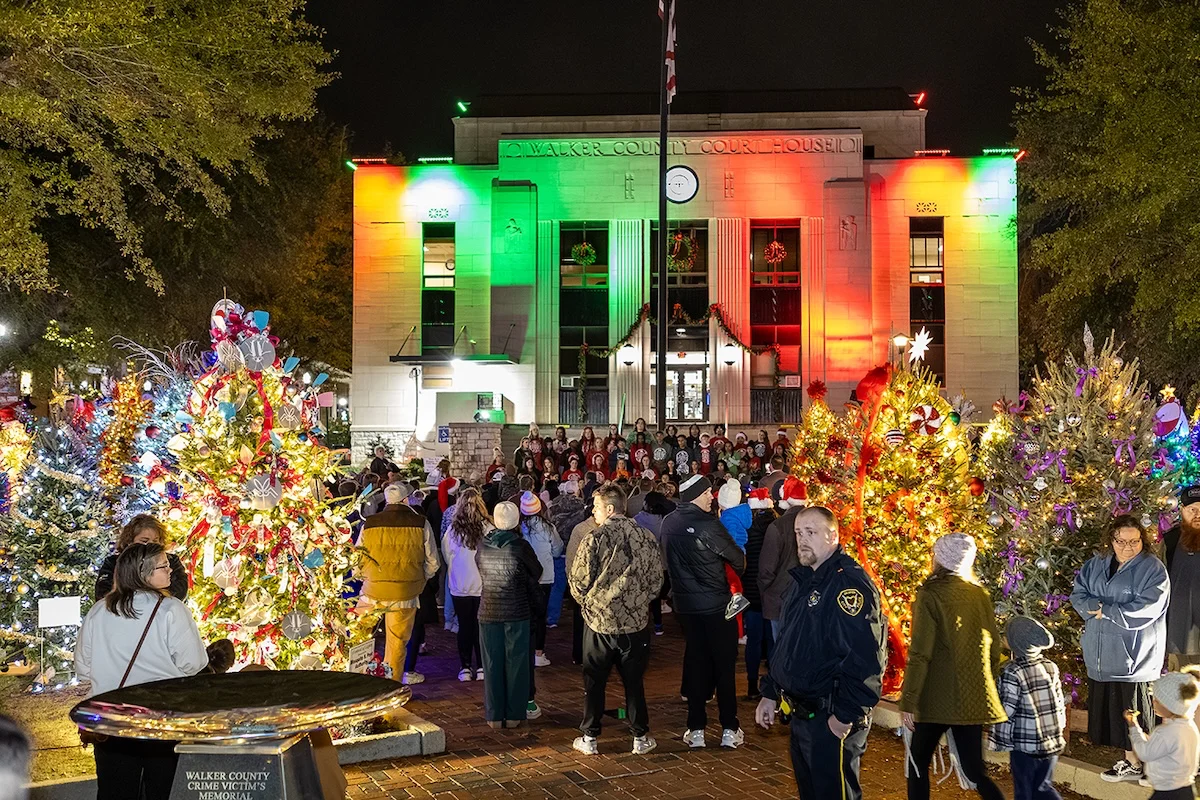 The Walker County Courthouse lit in Christmas colors behind decorated trees and festival visitors.