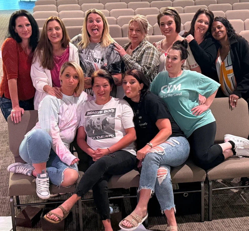 A group of women pose together and make playful faces.